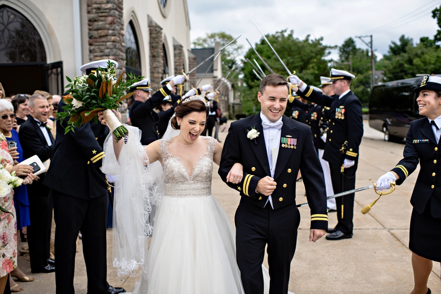 A groom is spanked with a sword after exiting the sword arch after their wedding.